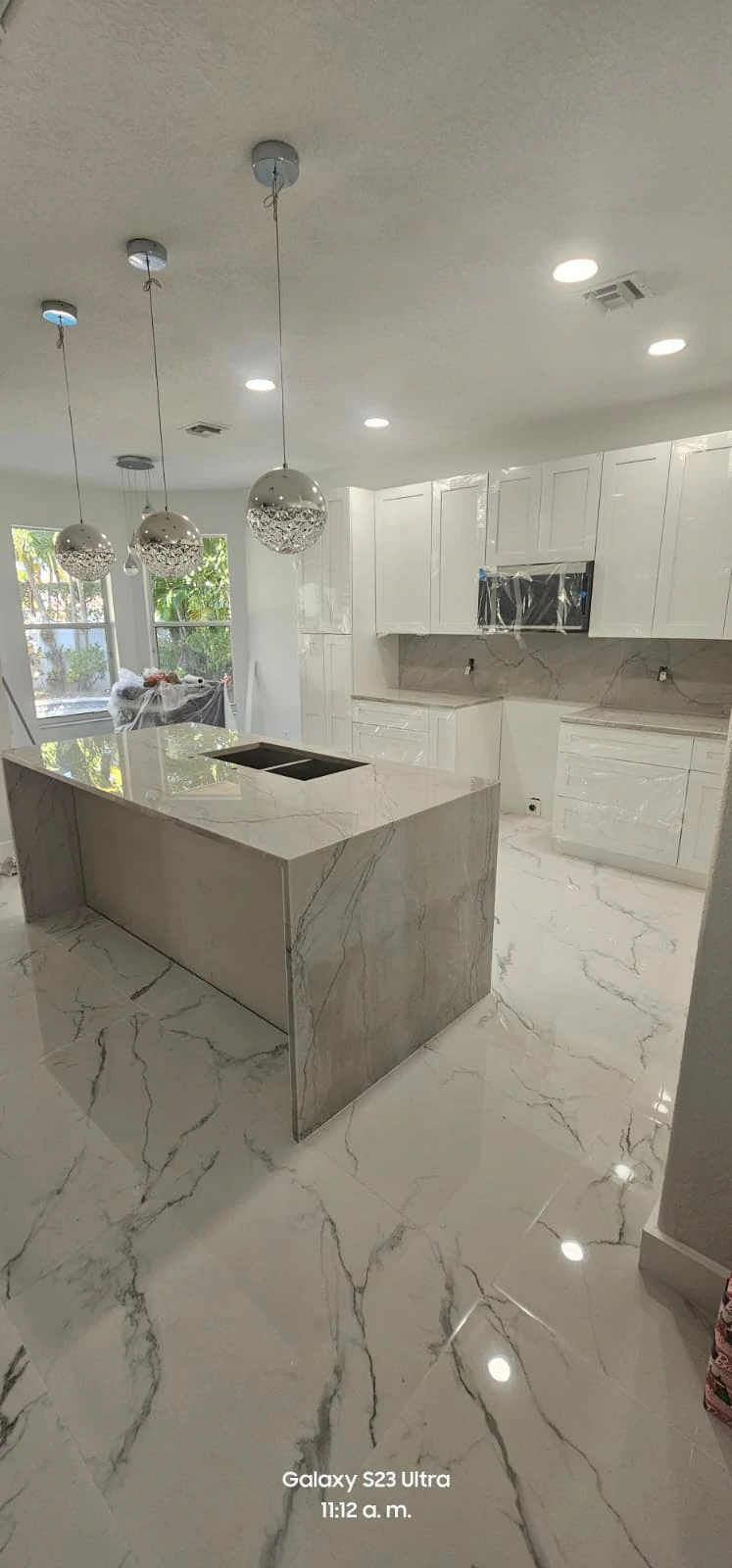 Cocina amplia con isla de granito y piso de mármol