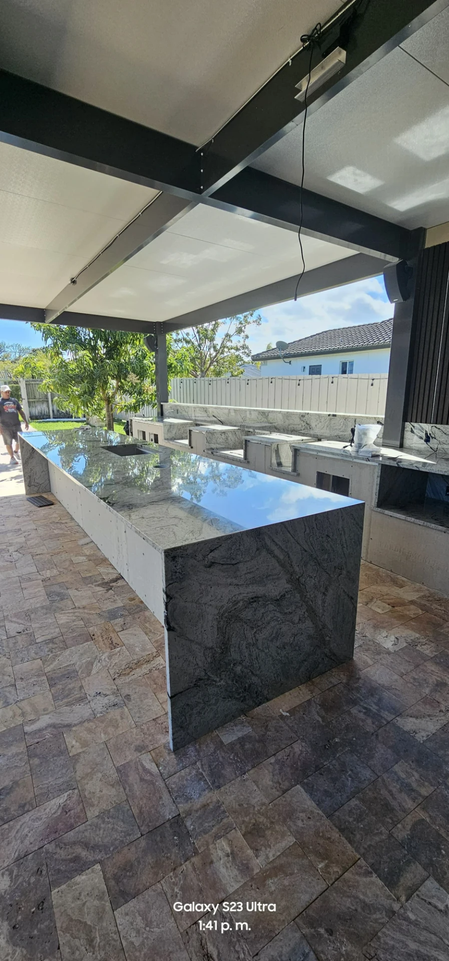 Cocina exterior con barra larga de granito pulido