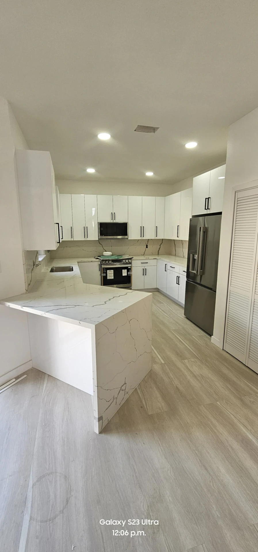 Cocina blanca con península de cuarzo veteado